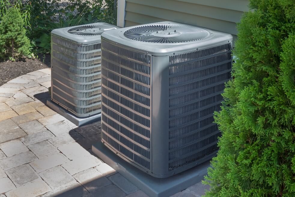 two air pumps, one smaller than the other, outside of a home