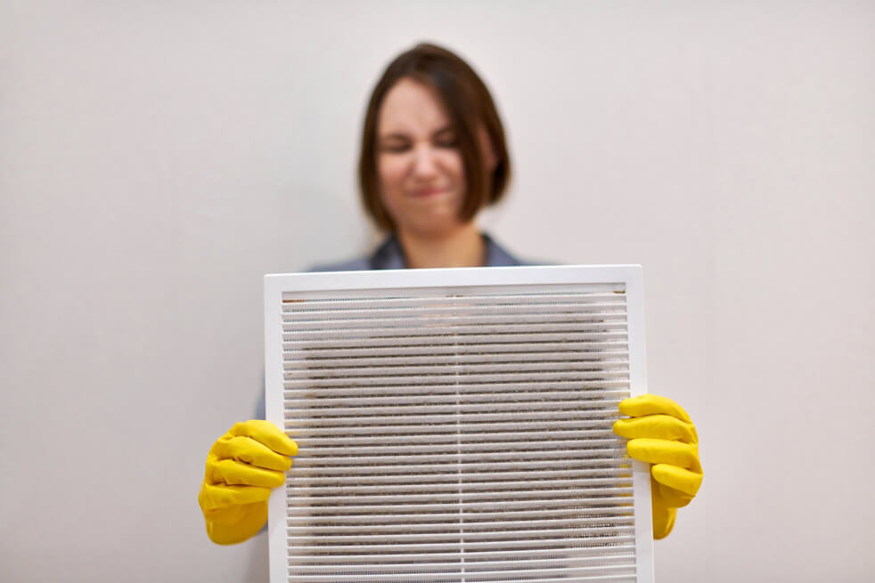 Woman holding dirty and dusty ventilation grille