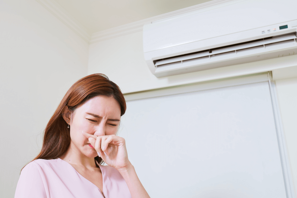 women holding nose to stinky air conditioner