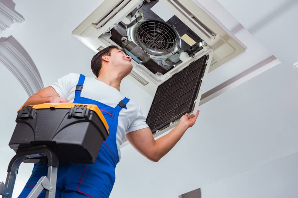 man on a step ladder looking at an indoor ac fan