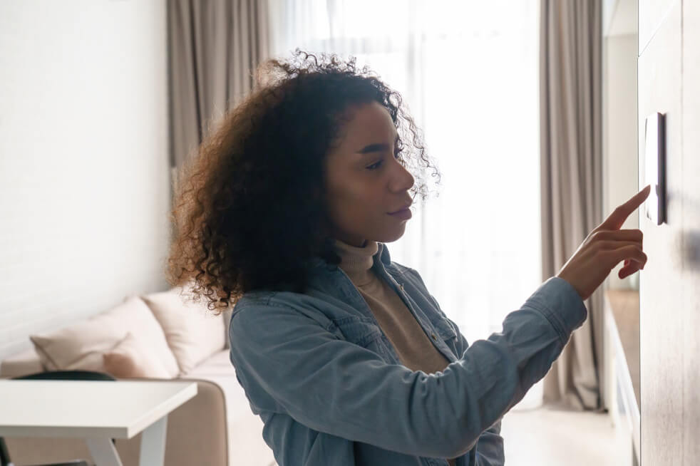 woman adjusting thermostat