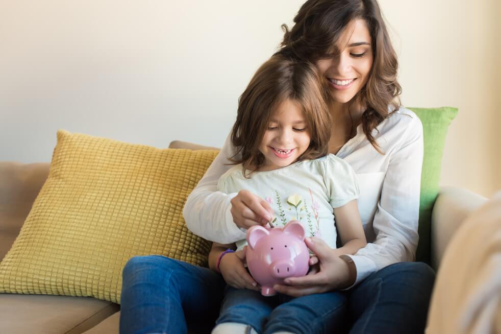 mother and young daughter filling piggy bank