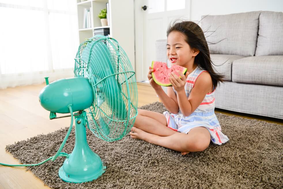 little girl sitting in front of fan