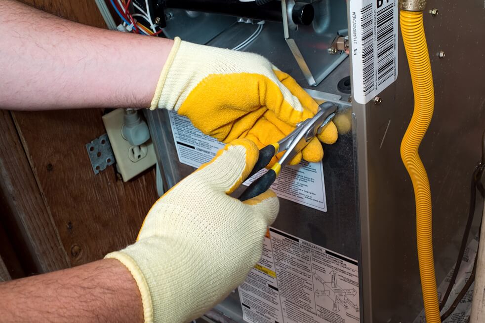 close up on HVAC technician repairing furnace