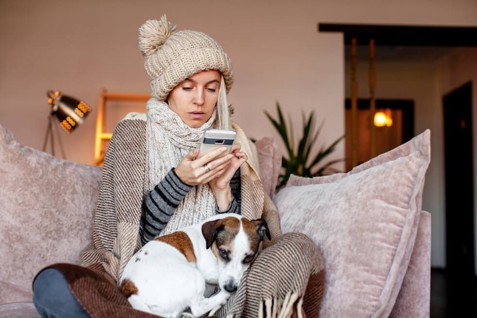 woman covered in winter clothes in home