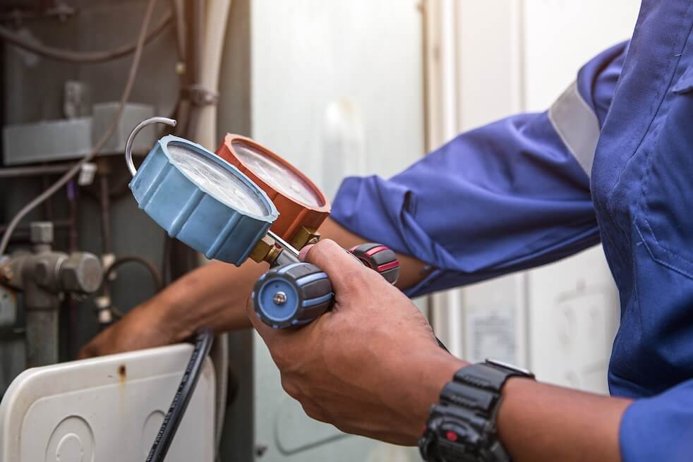 Heat and Air Conditioning, HVAC system service technician using measuring manifold gauge checking refrigerant and filling industrial air conditioner after duct cleaning maintenance outdoor compressor.